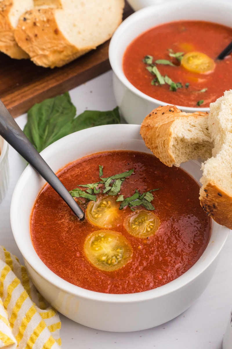 chilled tomato soup in bowl garnished with tomato and basil