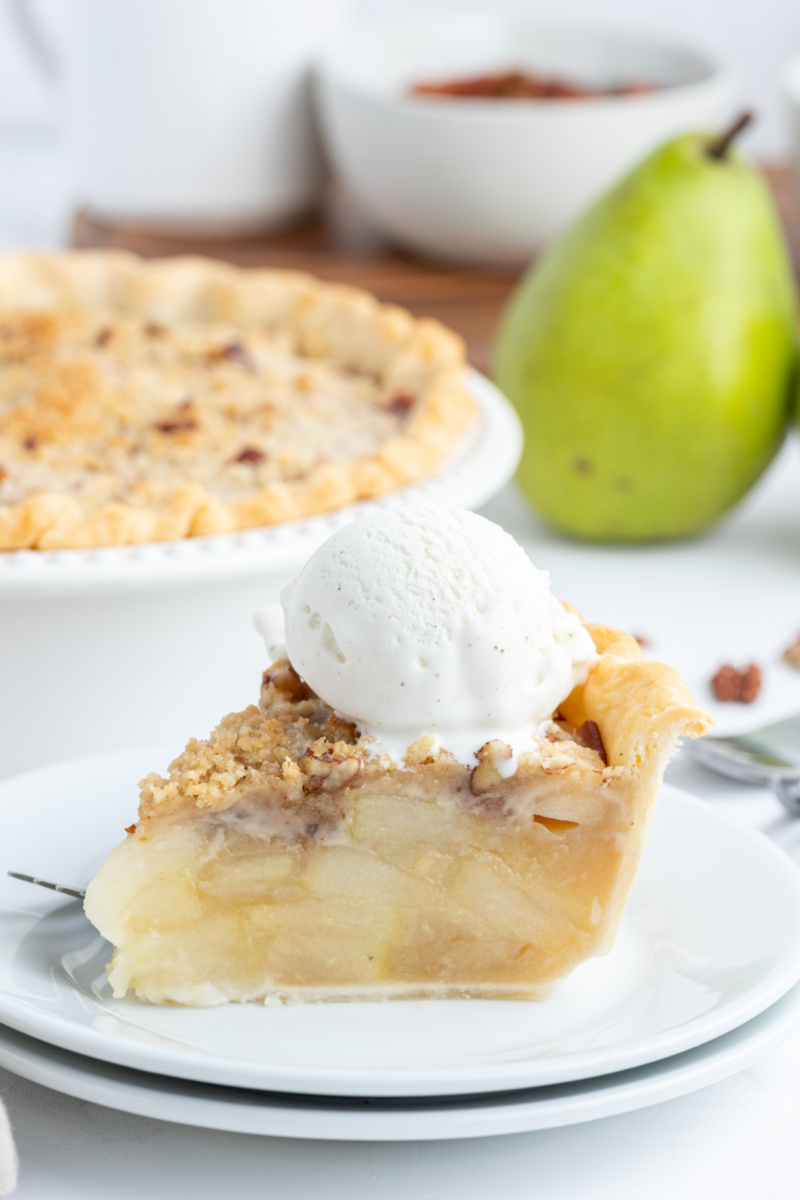 slice of ginger pear pie on a plate with scoop of vanilla ice cream on top