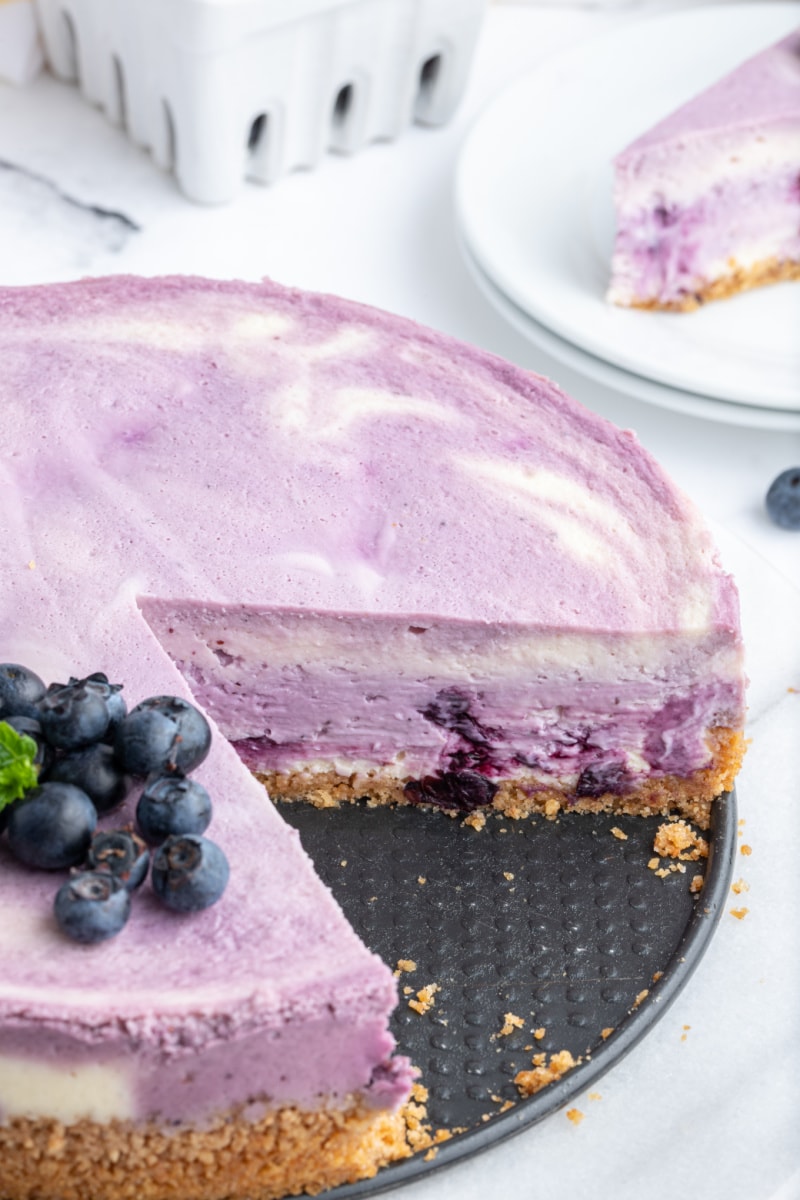 blueberry lemon cheesecake with big slice taken out of it
