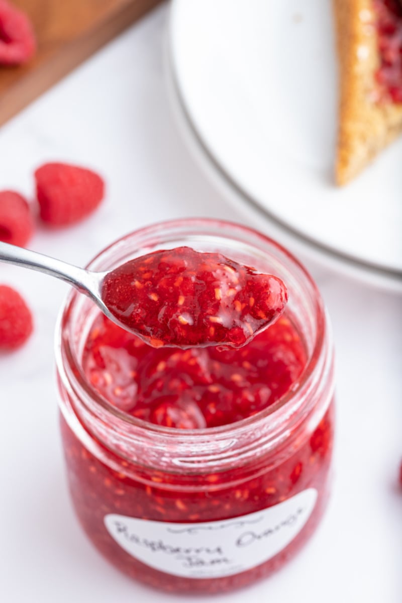 spooning out raspberry jam out of jar