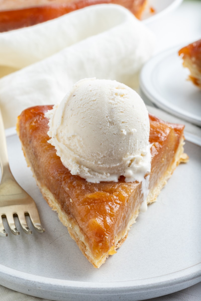 slice of apple tarte tatin on a plate with scoop of ice cream on top