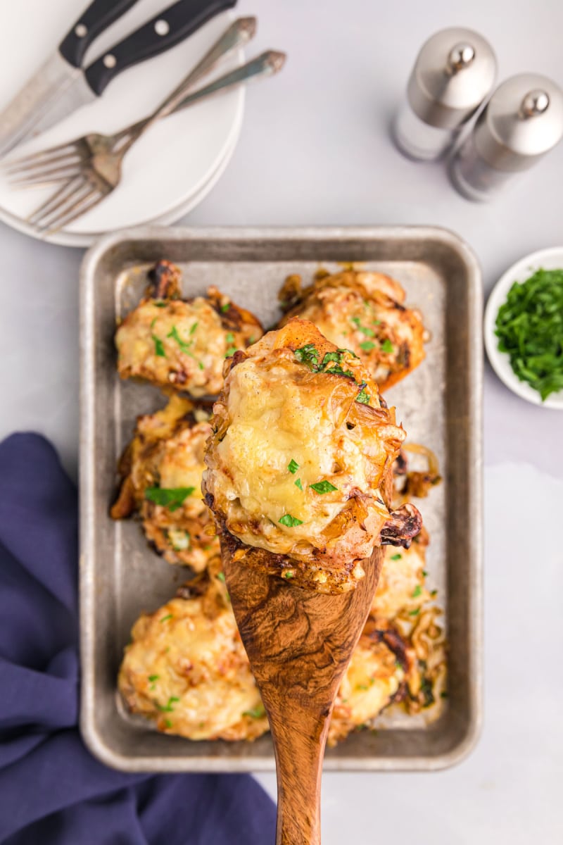 Spoon holding french onion sheet pan chicken