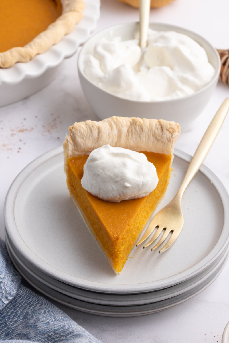 slice of pumpkin pie with whipped cream on a plate with fork