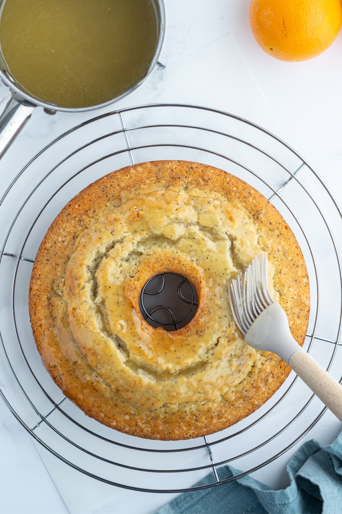 brushing sugar syrup onto almond orange poppy seed cake