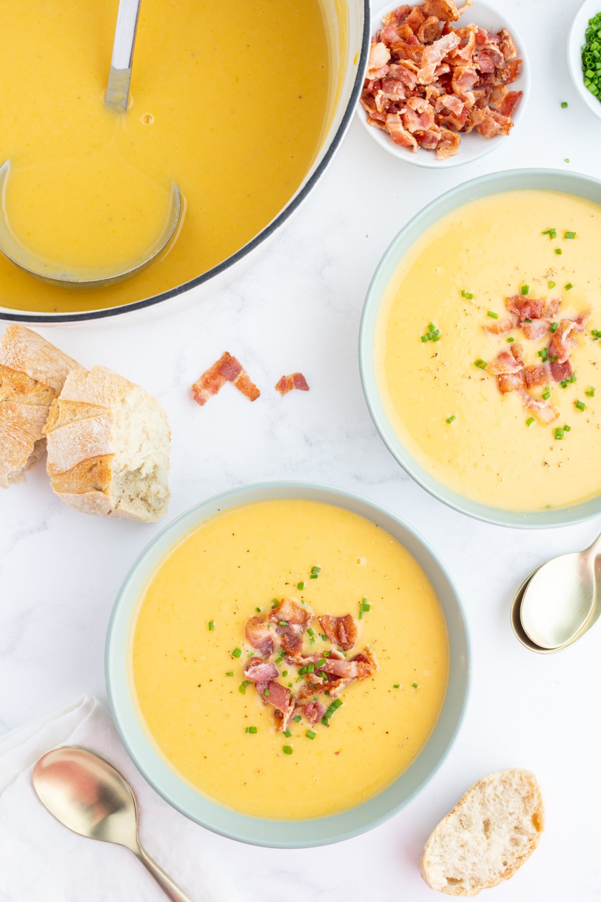 pot of butternut squash and potato soup with two bowl servings