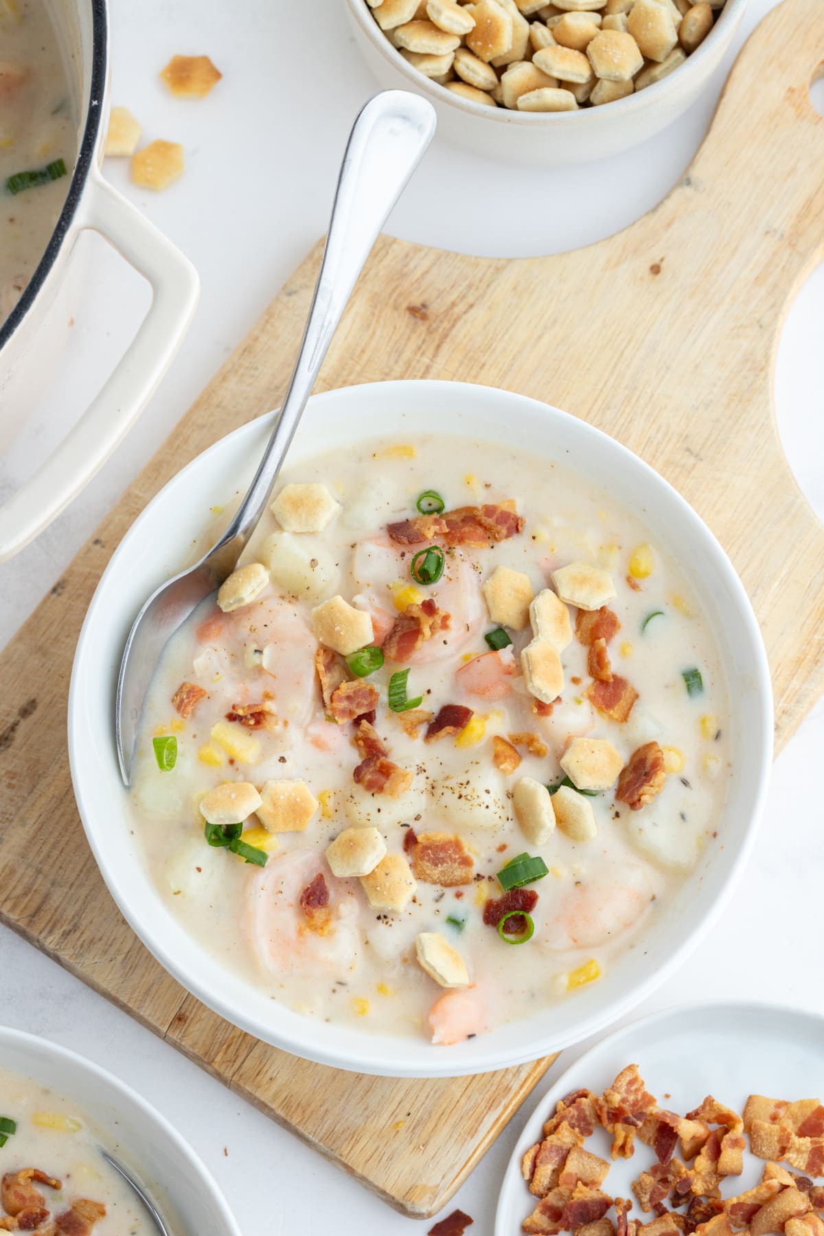 bowl of corn and shrimp chowder with spoon and bacon on top