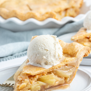 slice of maple apple pie on a plate with ice cream