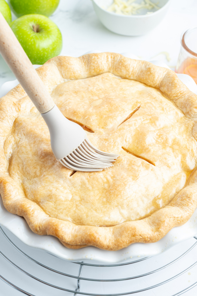 brushing maple syrup onto maple apple pie