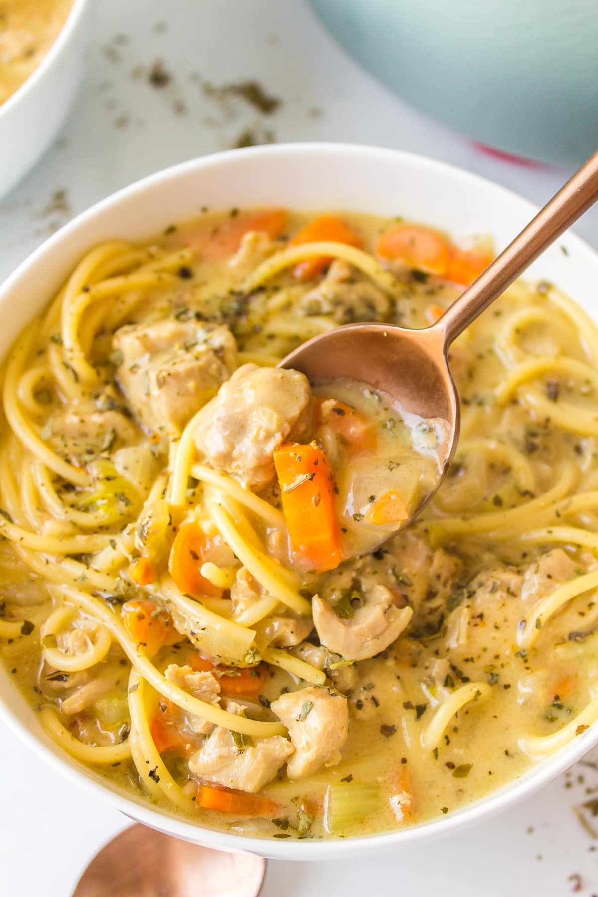 spooning out chicken alfredo soup from bowl