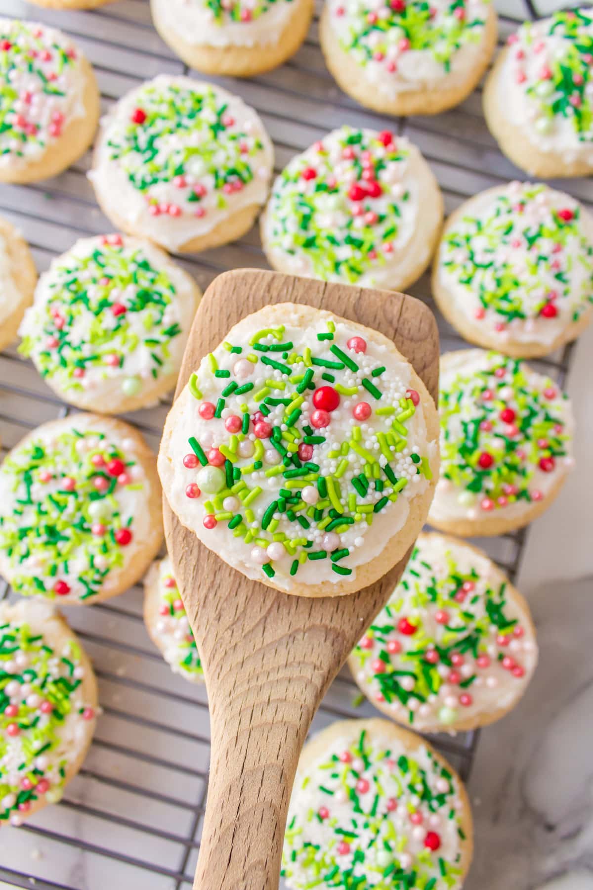 spatula holding christmas lofthouse cookie with the rest on a rack below