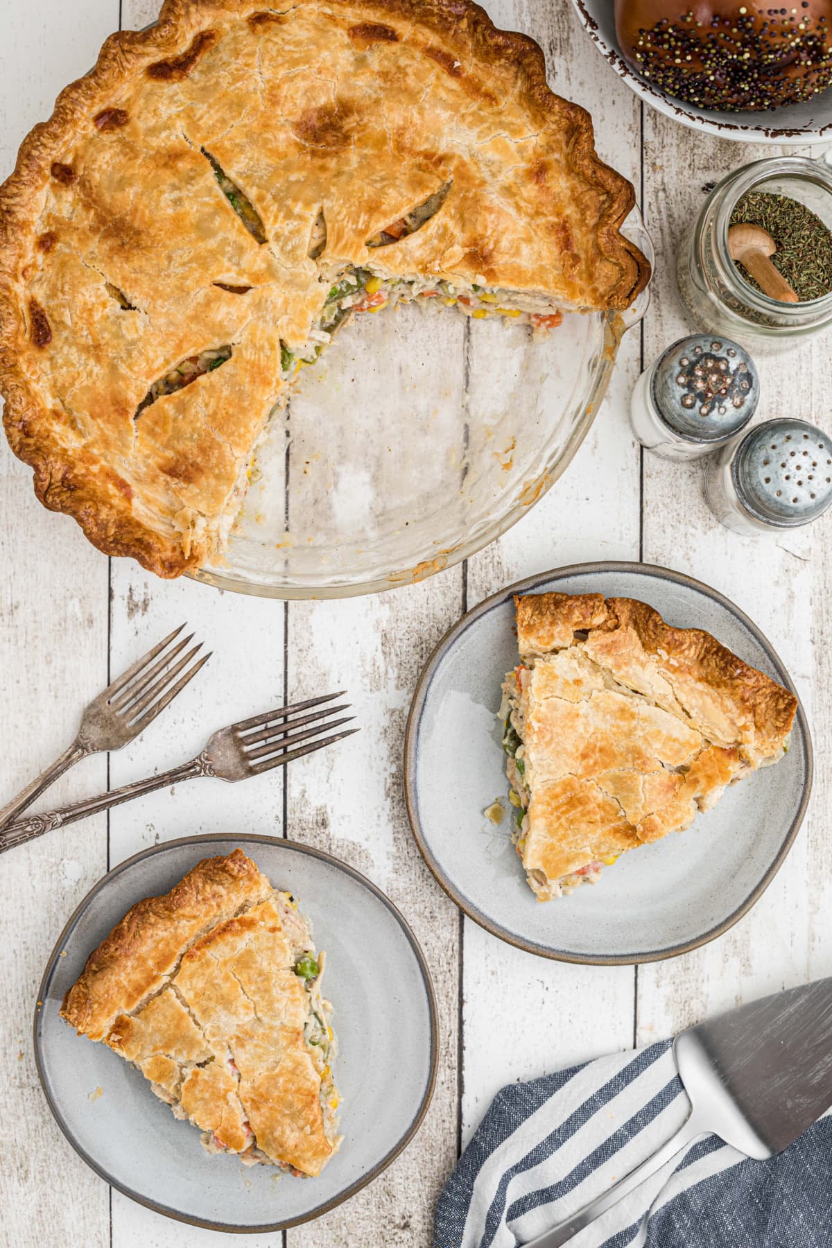 two slices of turkey pot pie on plates with rest of pie in background