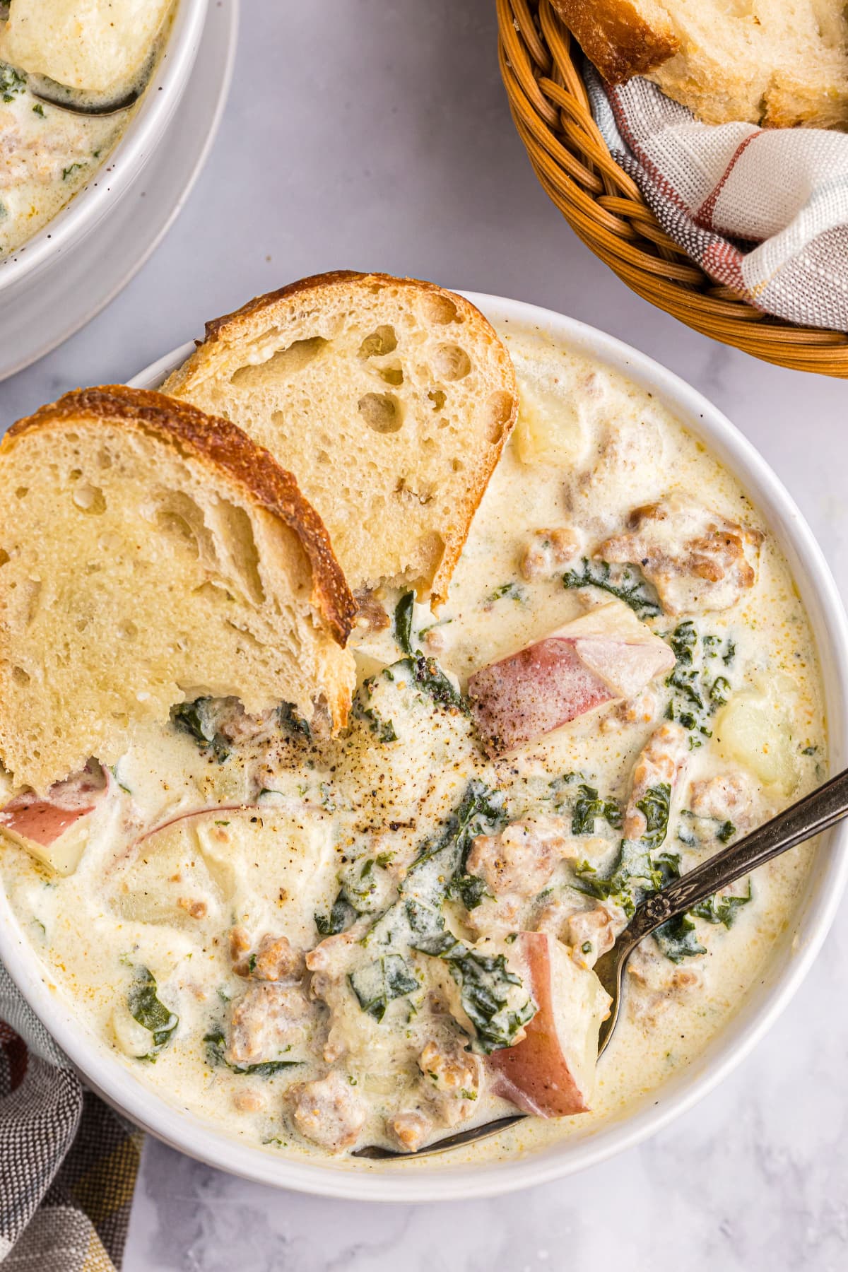 bowl of potato sausage and kale soup with slices of bread