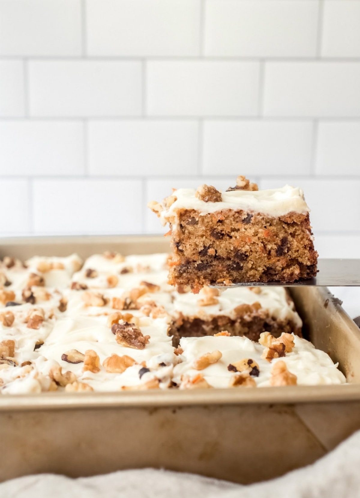 spatula taking slice of chocolate chip carrot cake out of cake