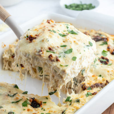 marry me chicken lasagna with spatula taking slice out of dish