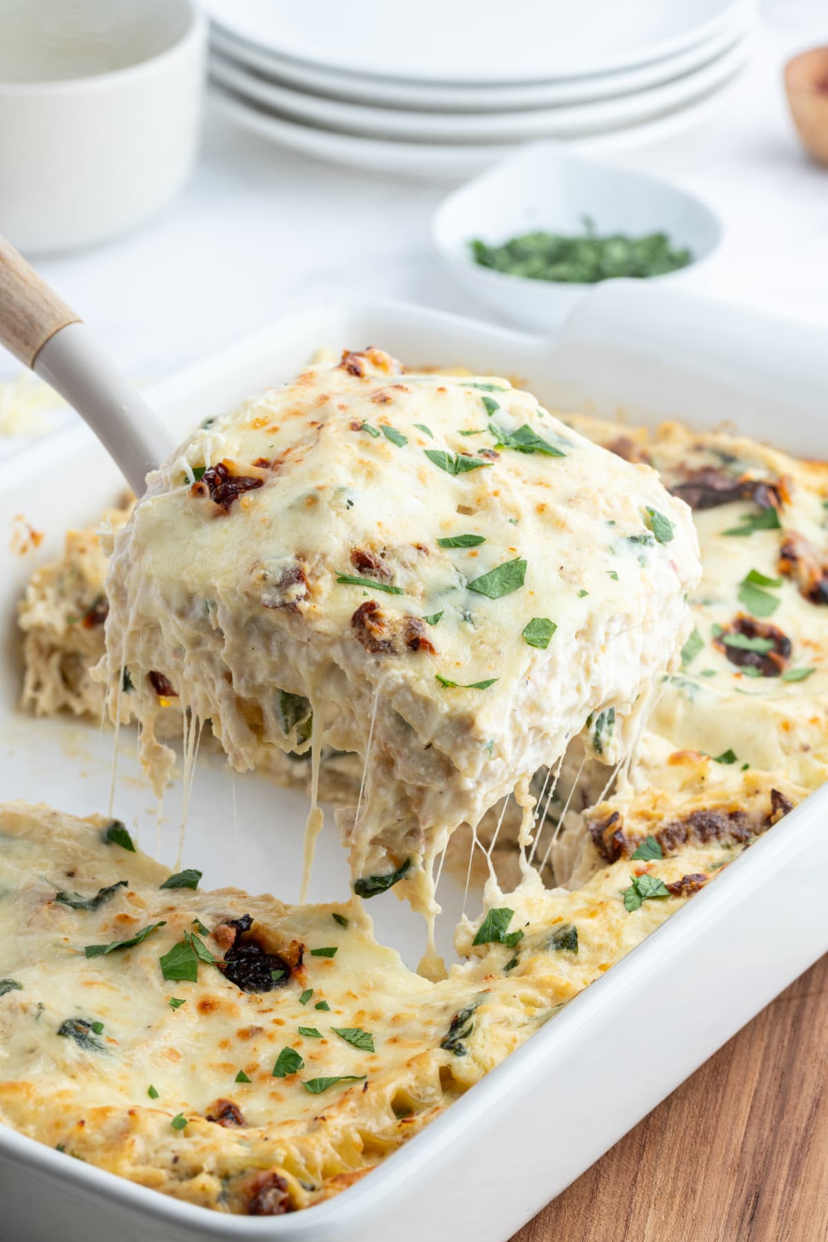 marry me chicken lasagna with spatula taking slice out of dish