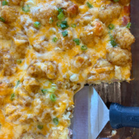tater tot breakfast casserole in dish with spatula taking out serving