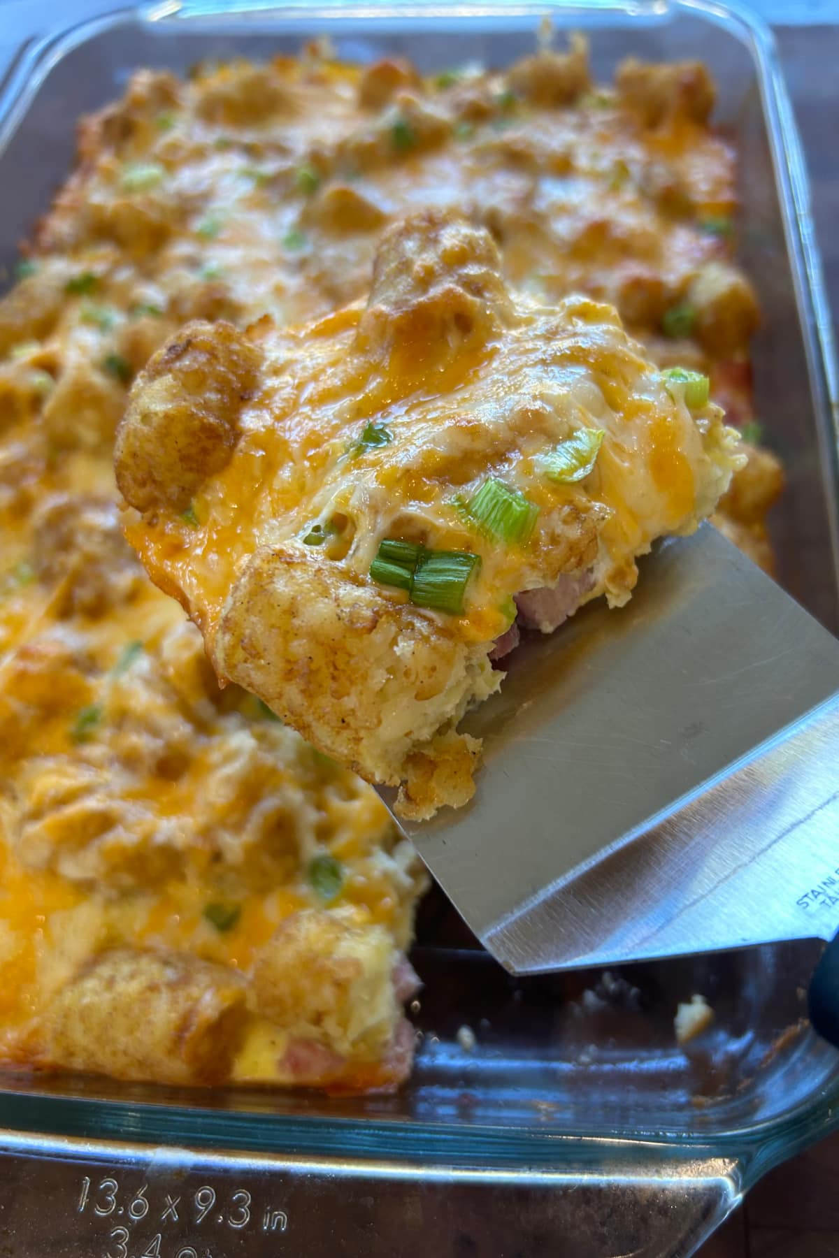 spatula taking out serving of tater tot breakfast casserole