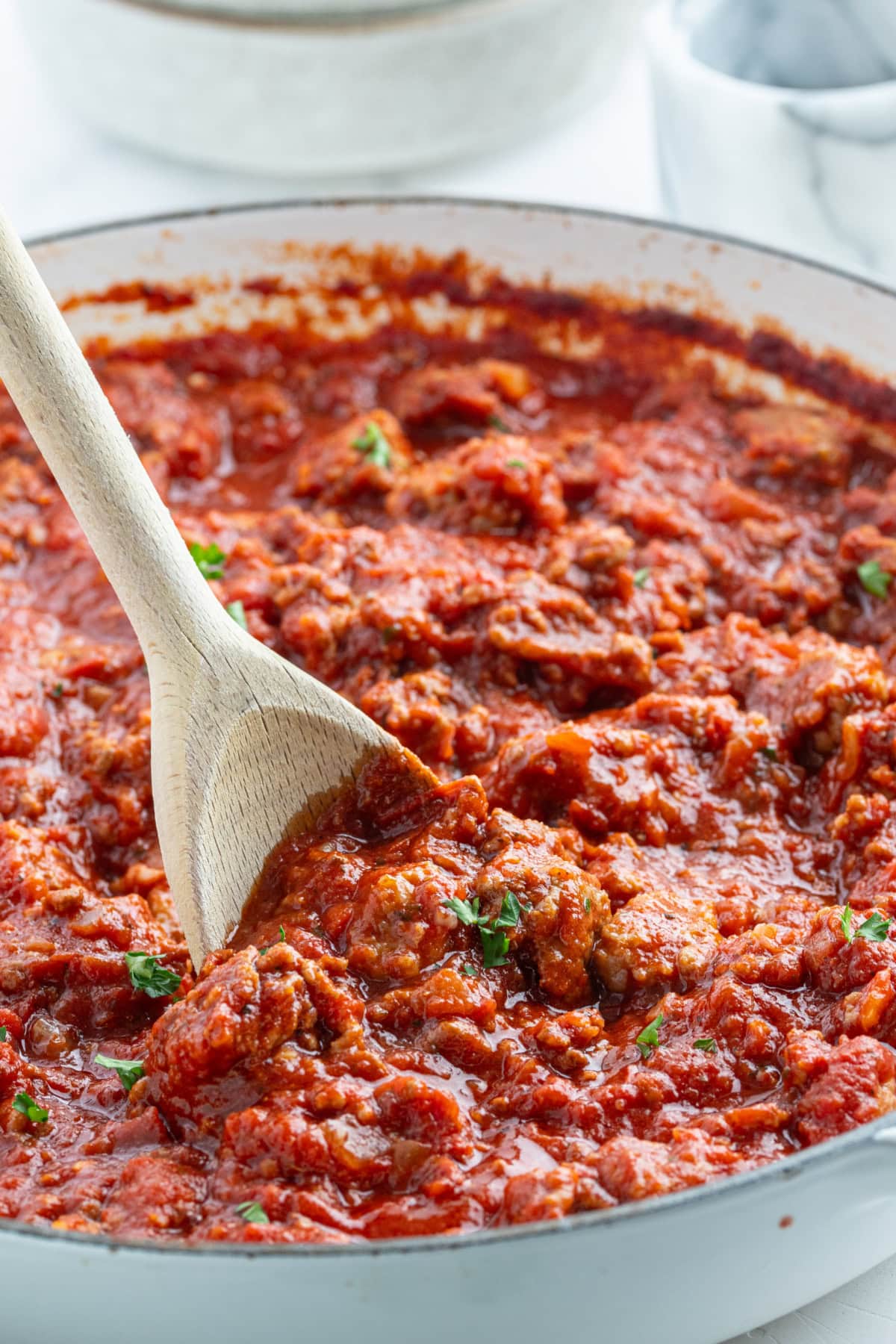 wooden spoon stirring meat sauce in pan