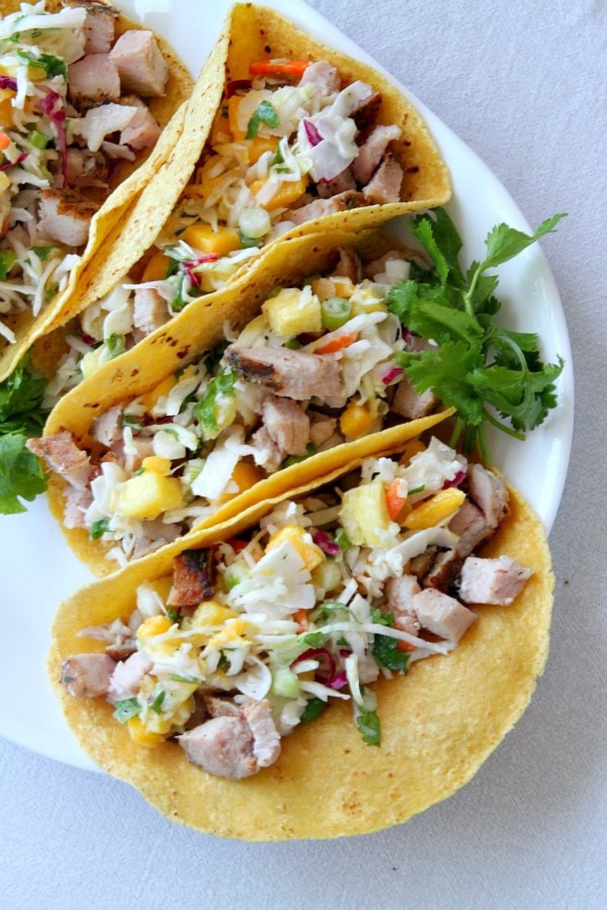 several grilled pork tacos with tropical slaw on plate