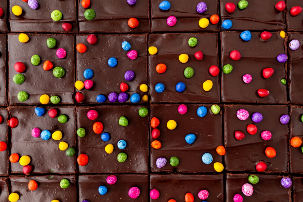 Cosmic Brownies are a fudgy, chocolatey copycat of the classic treat with ganache and colorful candy-coated chips. Easy and nostalgic! pan of cosmic brownies sliced into pieces