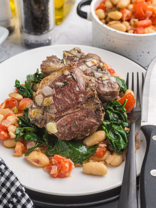 Broiled Lamb Loin Chop on plate with white beans and spinach