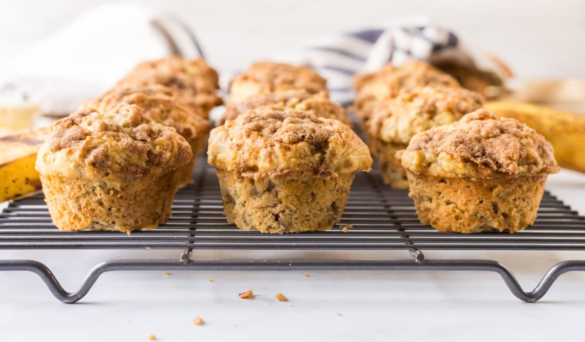 Gluten Free Banana Muffins that are soft, moist and topped with a sweet crumble. Easy to make and so good you’d never know they’re gluten-free! gluten free banana muffins on a cooling rack