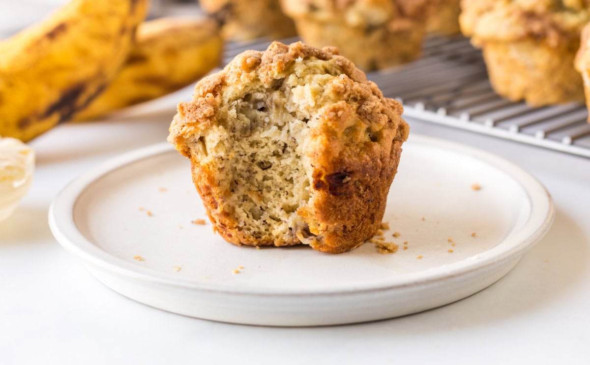 Gluten Free Banana Muffins that are soft, moist and topped with a sweet crumble. Easy to make and so good you’d never know they’re gluten-free! bite taken out of banana muffin