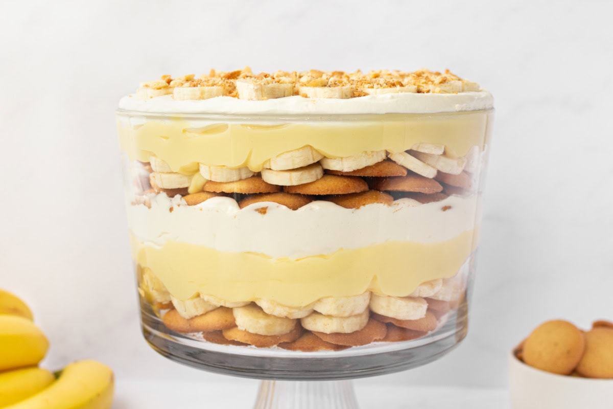 This Banana Pudding Trifle is the ultimate crowd-pleasing dessert! Layers of banana pudding, cheesecake whipped cream, fresh bananas, and Nilla wafers—easy and no bake! full shot of banana pudding trifle