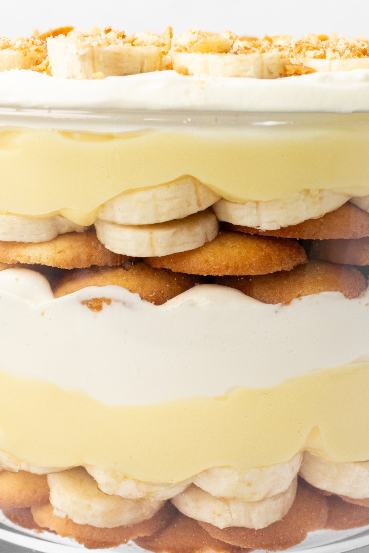 This Banana Pudding Trifle is the ultimate crowd-pleasing dessert! Layers of banana pudding, cheesecake whipped cream, fresh bananas, and Nilla wafers—easy and no bake! close up side of banana pudding trifle