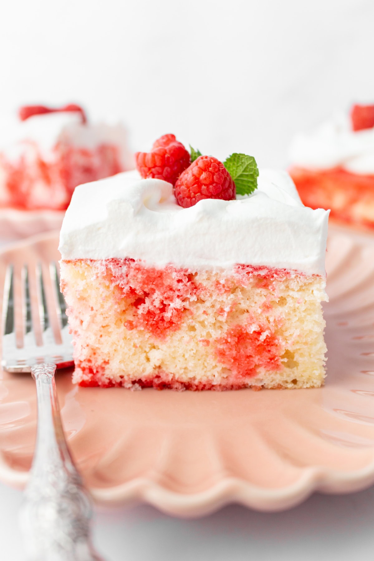 Easy Jello Poke Cake recipe from RecipeGirl.com : raspberry poke cake, strawberry poke cake slice of jello poke cake on a plate with fork