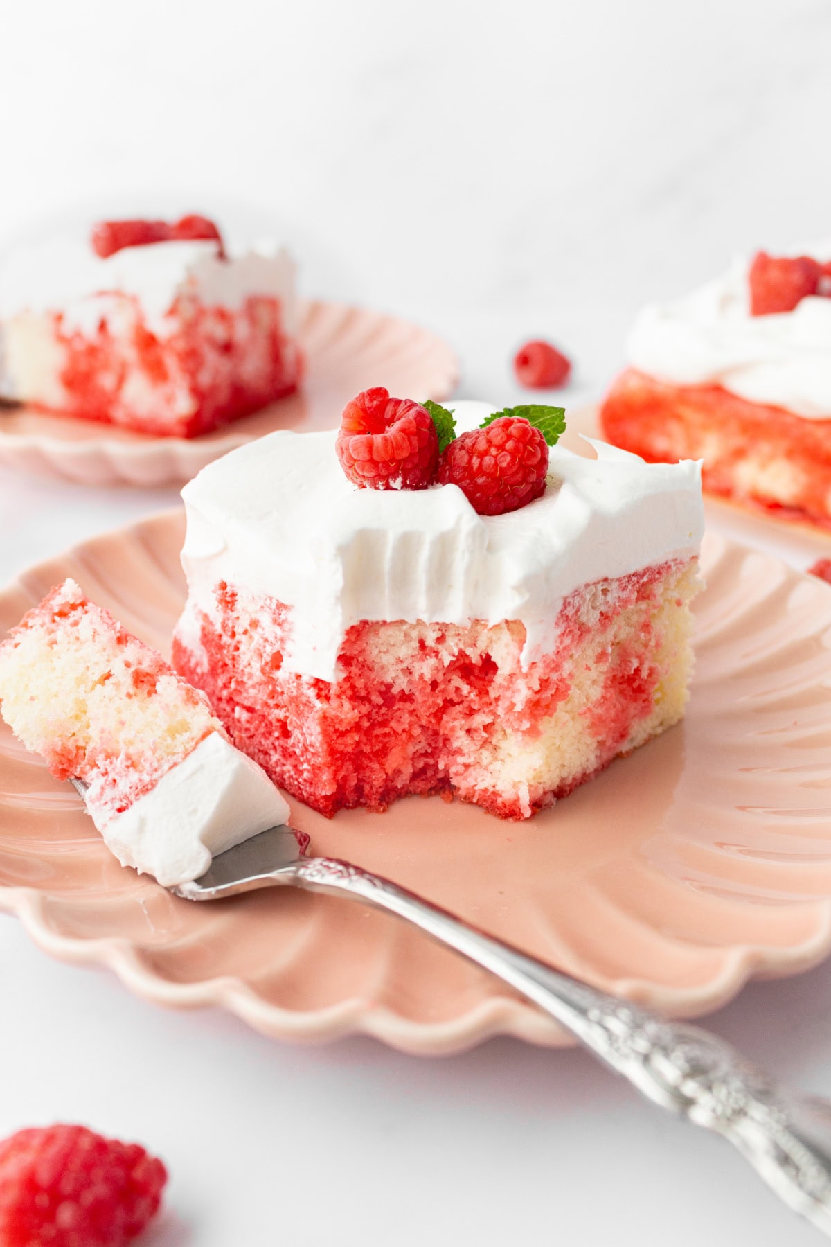 Easy Jello Poke Cake recipe from RecipeGirl.com : raspberry poke cake, strawberry poke cake slice of jello poke cake with fork bite taken out of it