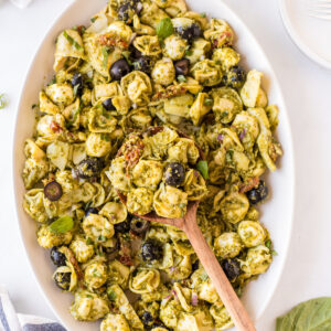 dish of pesto tortellini pasta salad with wooden spoon