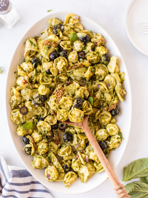 dish of pesto tortellini pasta salad with wooden spoon
