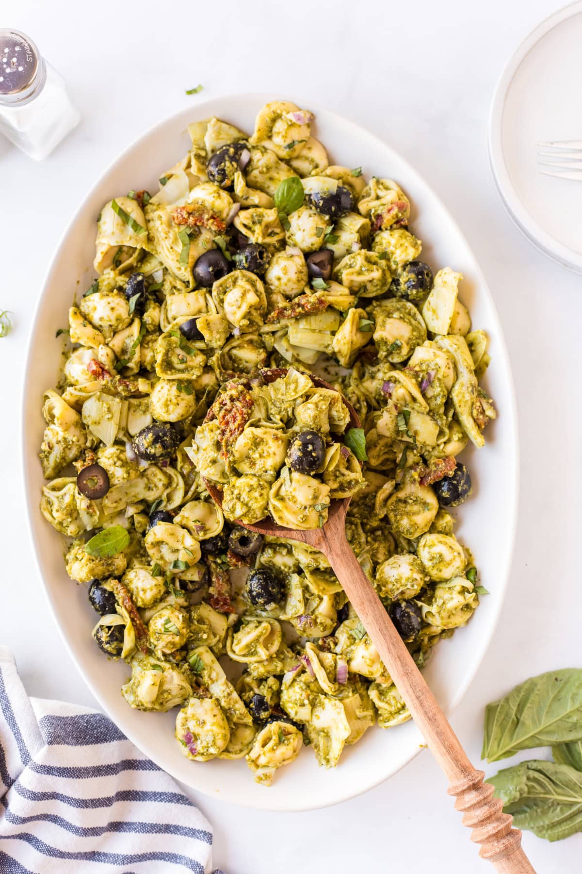 Pesto Tortellini Pasta Salad recipe from RecipeGirl.com dish of pesto tortellini pasta salad with wooden spoon