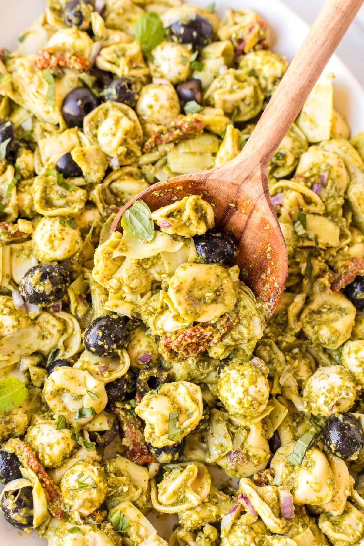 Pesto Tortellini Pasta Salad recipe from RecipeGirl.com spoon in bowl of pesto tortellini pasta salad