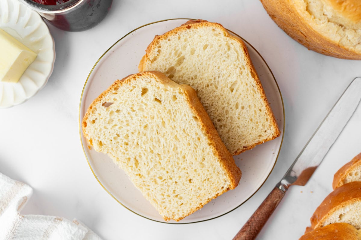 Sally Lunn bread is a soft, slightly sweet old-fashioned favorite yeast bread baked in a tube pan. Perfect for brunch or serving warm with butter and jam! Soft, buttery and so good. two slices of sally lunn bread on a plate