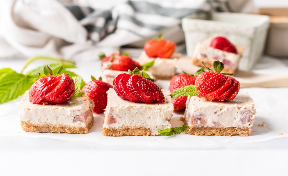Strawberry Cheesecake Bars recipe from RecipeGirl.com strawberry cheesecake bars garnished with fresh strawberries