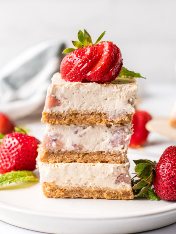 three strawberry cheesecake bars stacked on plate