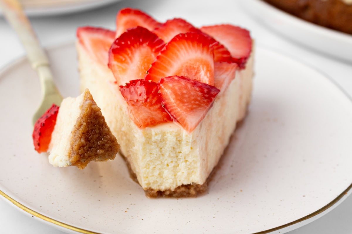 slice of strawberry cheesecake with bite sliced out of it