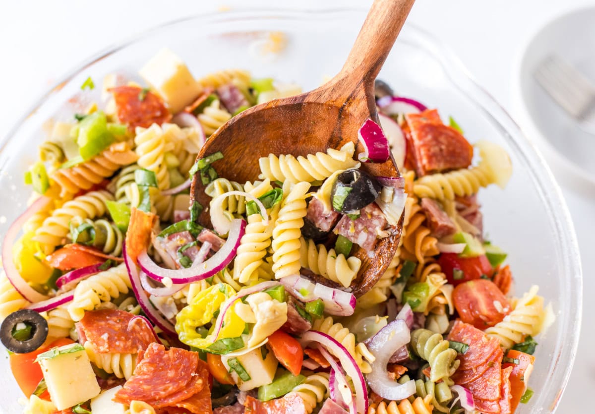 Antipasto Pasta Salad Recipe from RecipeGirl.com wooden spoon in bowl of pasta salad