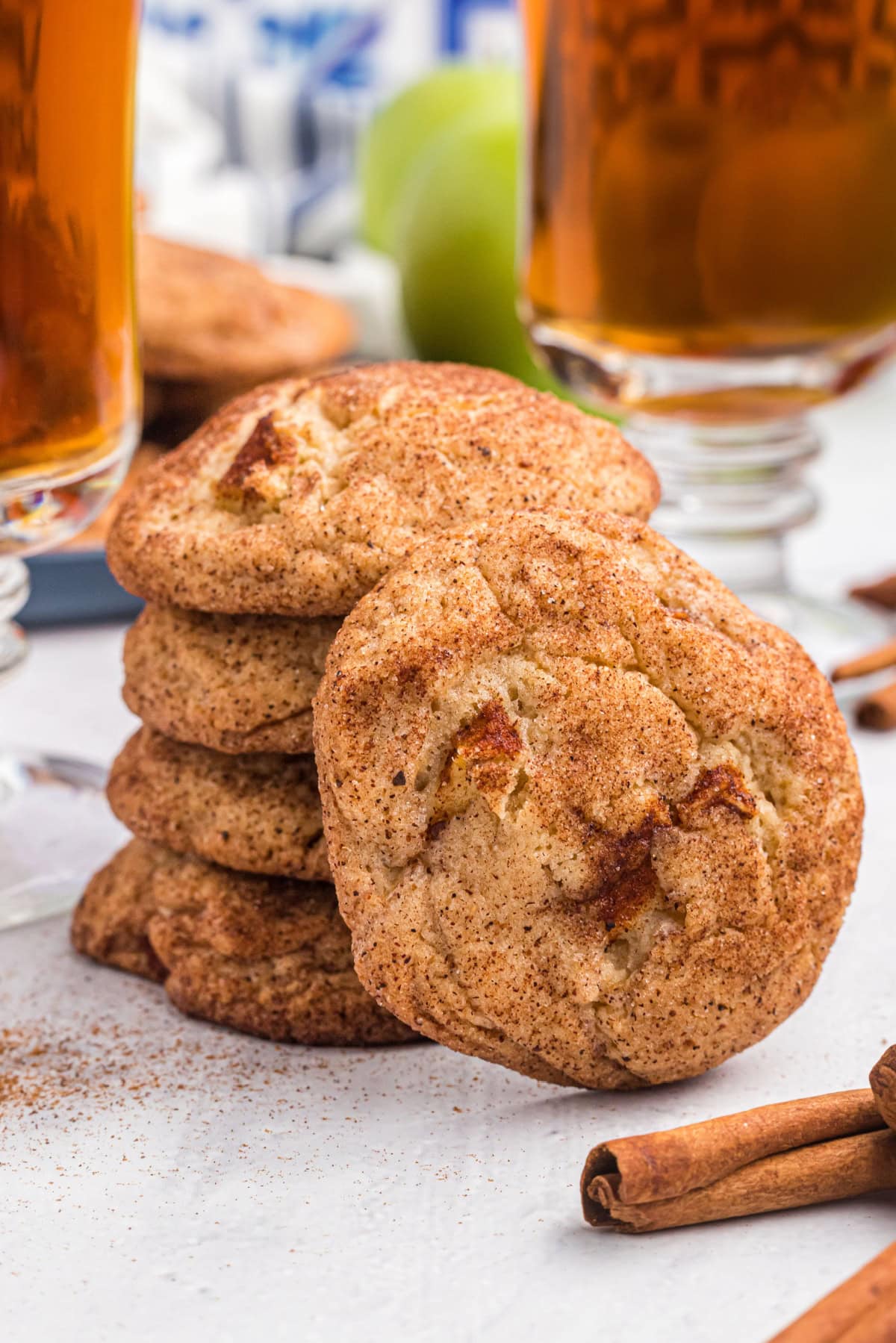 Apple Snickerdoodles are traditional snickerdoodles filled with apple cider syrup and fresh apples to create the perfect fall cookie recipe. Recipe from RecipeGirl.com stack of apple snickerdoodles and one on the side