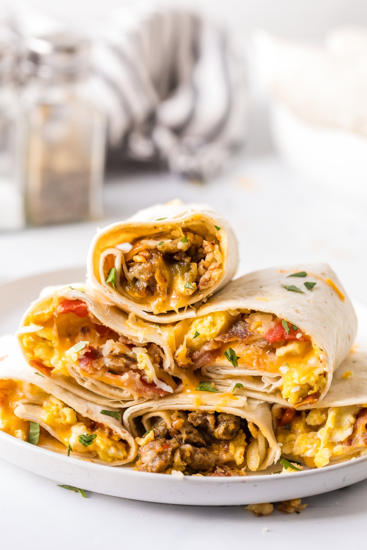 How to make Breakfast Burritos recipe from RecipeGirl.com : scrambled eggs, sausage, hash browns and cheese stack of breakfast burritos on a plate