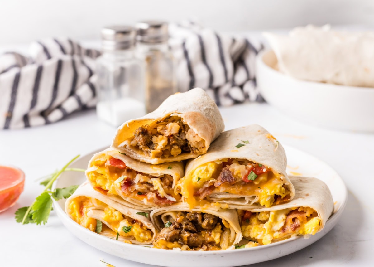 How to make Breakfast Burritos recipe from RecipeGirl.com : scrambled eggs, sausage, hash browns and cheese stack of breakfast burritos on a platter