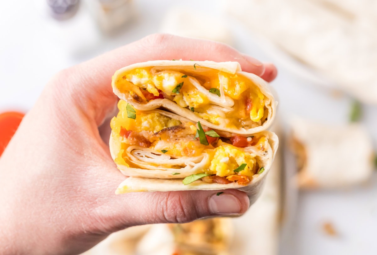 How to make Breakfast Burritos recipe from RecipeGirl.com : scrambled eggs, sausage, hash browns and cheese hand holding breakfast burritos