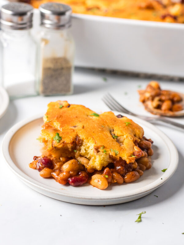 Serving of beans and cornbread casserole with melted cheese and herbs.