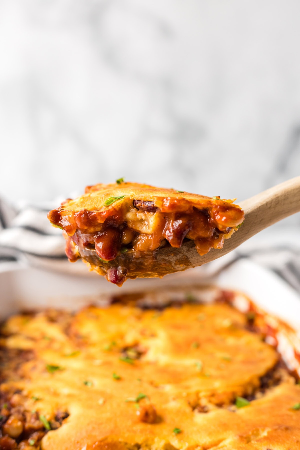 Cowboy Casserole is a hearty, baked beans and cornbread casserole full of smoky, sweet, and savory flavor — perfect for cozy family dinners or potlucks! Recipe from RecipeGirl.com. spoonful of beans and cornbread casserole