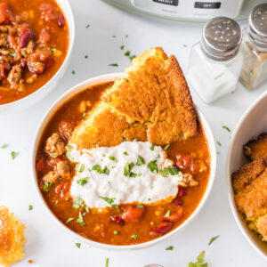 easy slow cooker chili serving in bowl with cornbread and sour cream