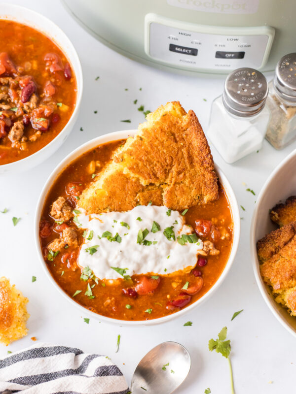 easy slow cooker chili serving in bowl with cornbread and sour cream