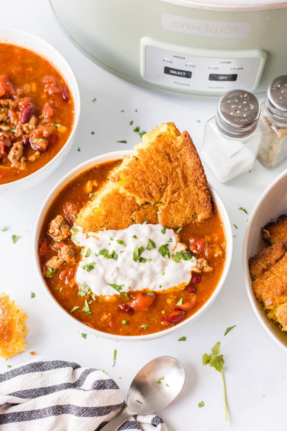 This Easy Slow Cooker Chili is the ultimate comfort food — loaded with ground beef or turkey, beans, and bold spices. A simple, hearty meal that’s perfect for cozy nights, game days, or meal prep! Hearty crockpot chili topped with  cornbread and sour cream