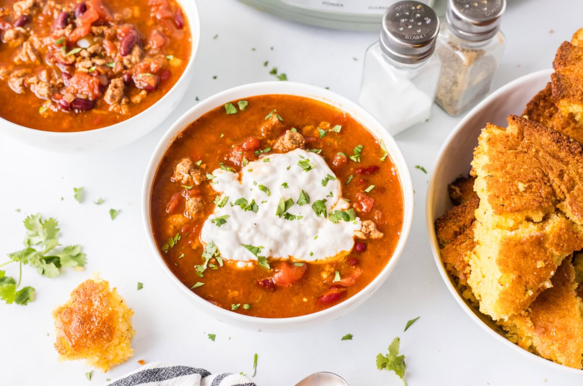 This Easy Slow Cooker Chili is the ultimate comfort food — loaded with ground beef or turkey, beans, and bold spices. A simple, hearty meal that’s perfect for cozy nights, game days, or meal prep! Bowl of easy slow cooker chili with beef and beans topped with sour cream